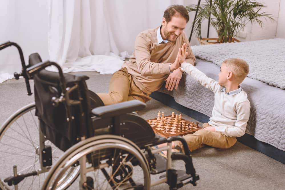 father with son in wheelchair playingchess